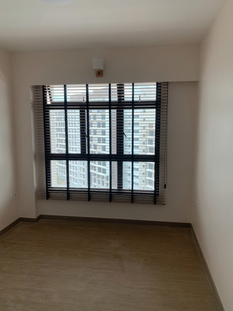 Black timber venetian blinds in a bedroom overlooking nearby HDB blocks