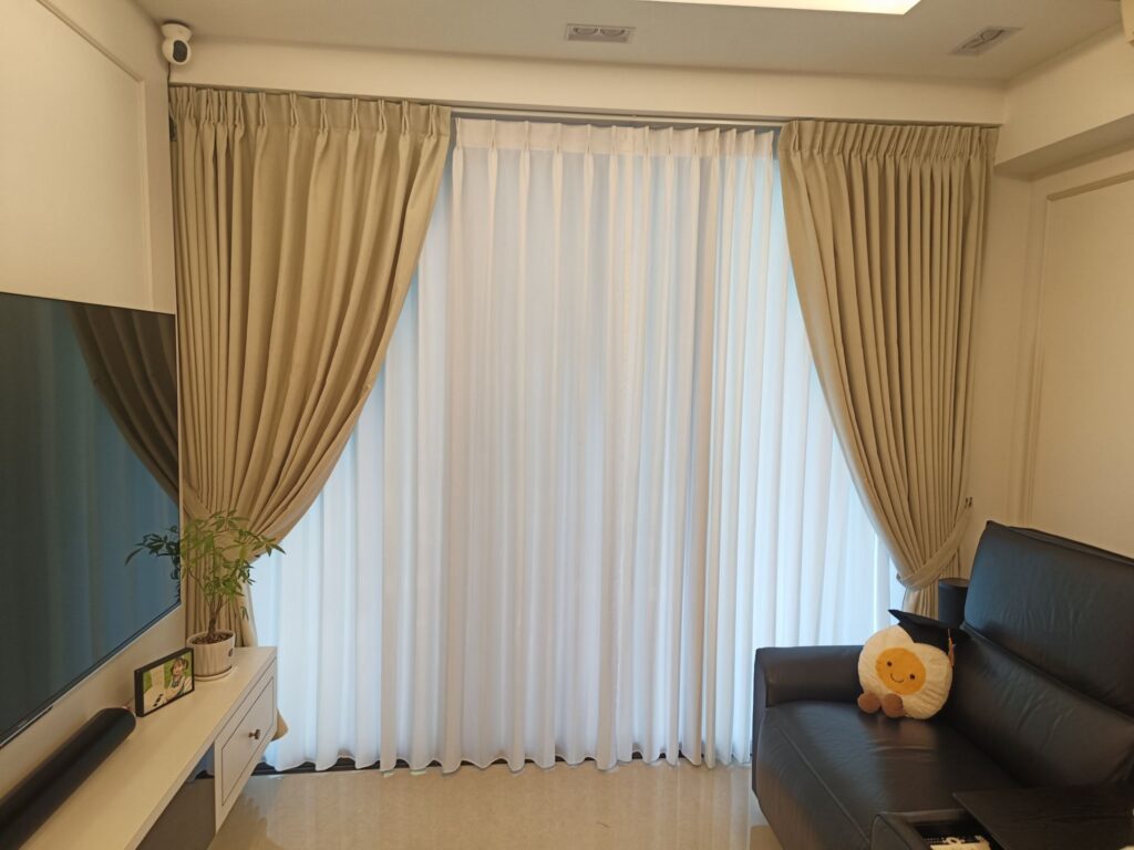 Day and night curtains in a Singapore living room, beige pinch-pleat drapes layered with white sheers