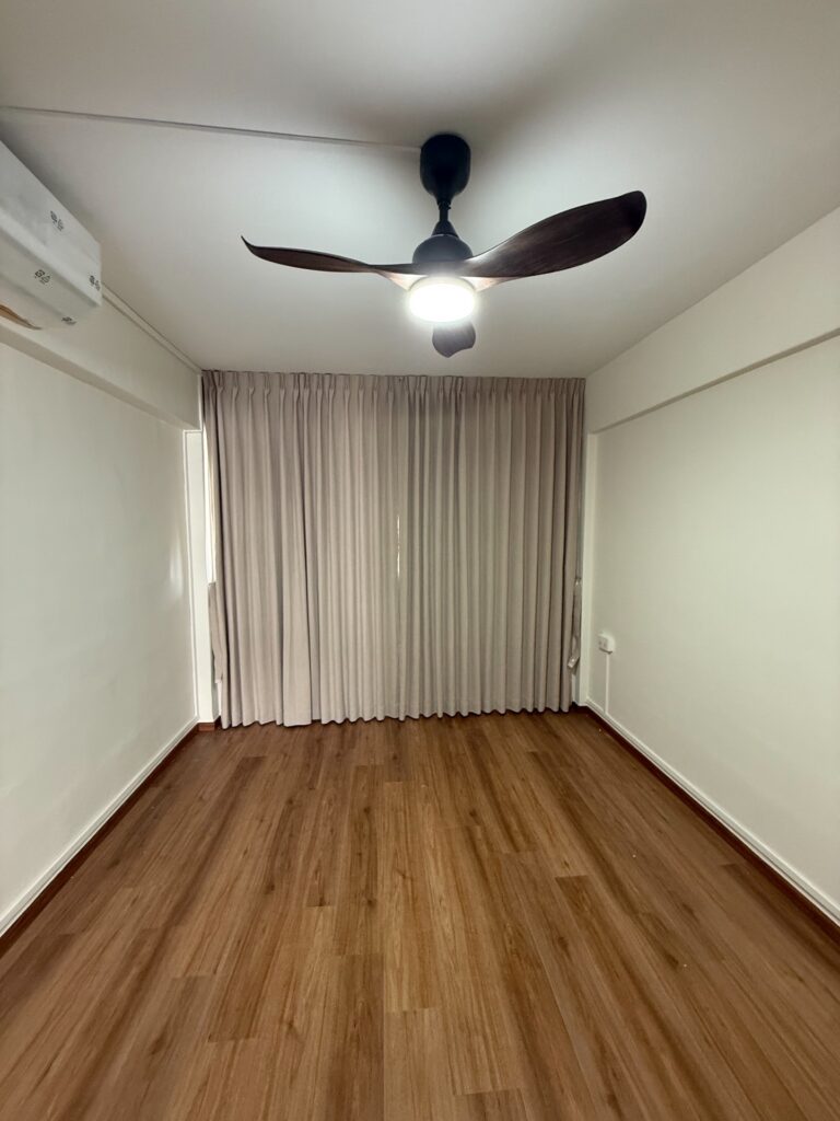 Grey pinch-pleat curtains dressing a full-height bedroom window with wood flooring