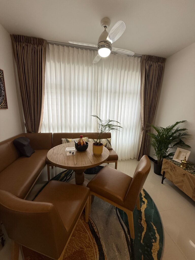 White sheer day curtains with brown pinch-pleat side curtains framing a dining nook in a Singapore home